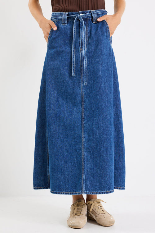 Person wearing a blue denim skirt on a white background