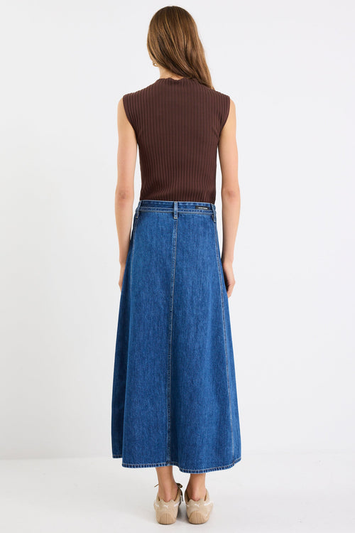 Woman wearing a brown sleeveless top and blue denim skirt on a white background