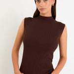 Woman wearing a brown sleeveless ribbed top against a white background
