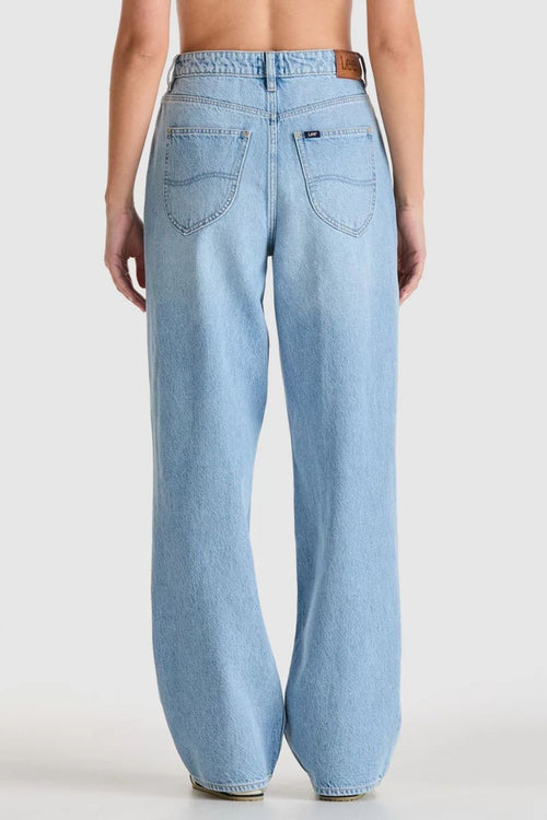 light blue high-rise wide leg jeans with patch pockets and leather logo patch on waistband. Model wears them full length with relaxed fit through the legs.