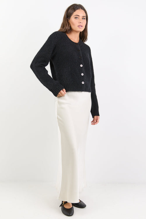 Woman wearing a black cardigan and white skirt on a white background