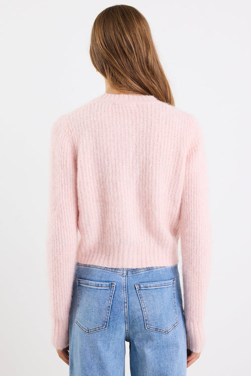 Person wearing a light pink sweater and blue jeans on a white background
