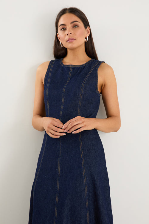 Woman wearing a dark blue sleeveless dress against a white background