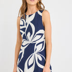 Woman wearing a navy sleeveless mini dress with a bold cream abstract print, styled simply with natural makeup and soft waves.