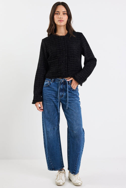 Person wearing a black sweater and blue jeans on a white background