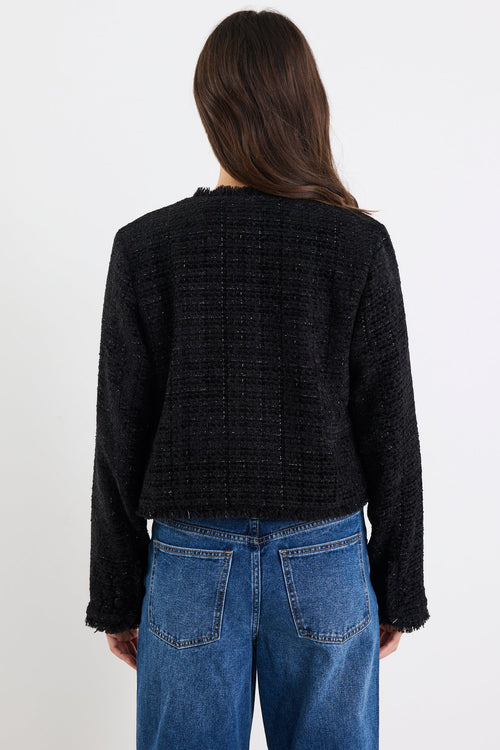 Person wearing a black textured sweater and blue jeans against a white background