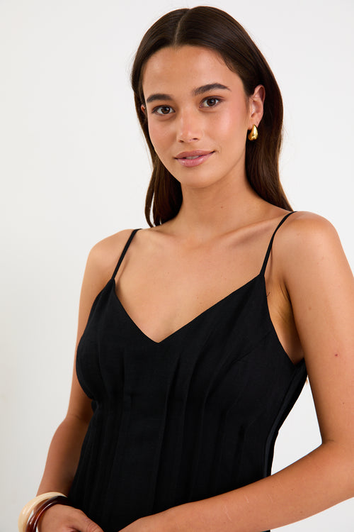 Model wearing a black strappy linen-blend maxi dress with a pleated bodice and an A-line flowing skirt.
