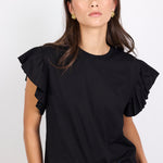 Woman wearing a black top with ruffled sleeves against a white background