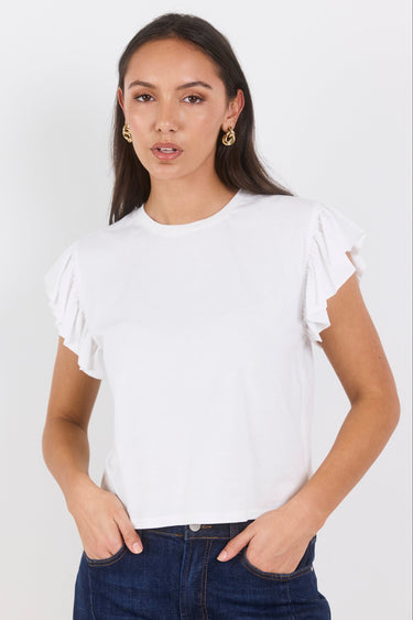 Woman wearing a white ruffled top and dark jeans on a white background