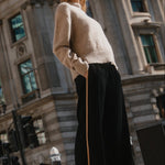 Woman standing on a street corner with a large building in the background