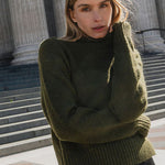 Woman in a green sweater standing in front of classical architecture