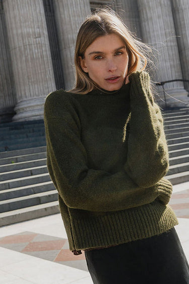 Woman in a green sweater standing in front of classical architecture