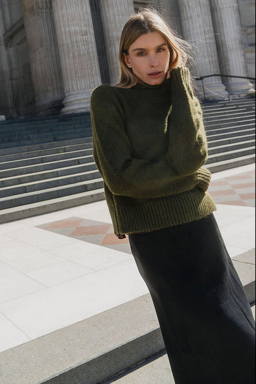 Woman in a green sweater standing in front of classical architecture