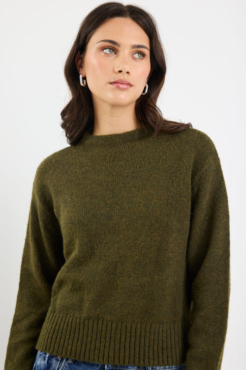 Woman wearing an olive green sweater against a white background