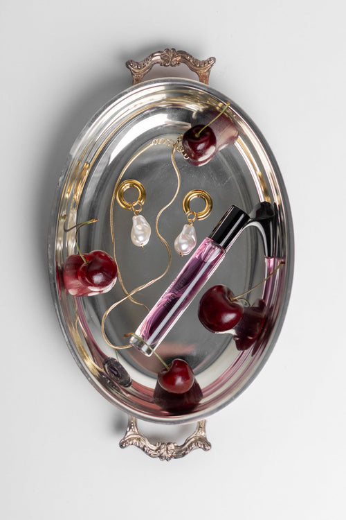 Silver tray with jewelry and cherry decorations on a light gray background