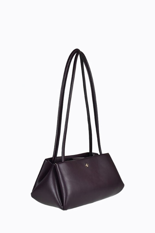 A dark chocolate leather shoulder bag with a single long strap and a small gold logo on the front, set against a plain white background.