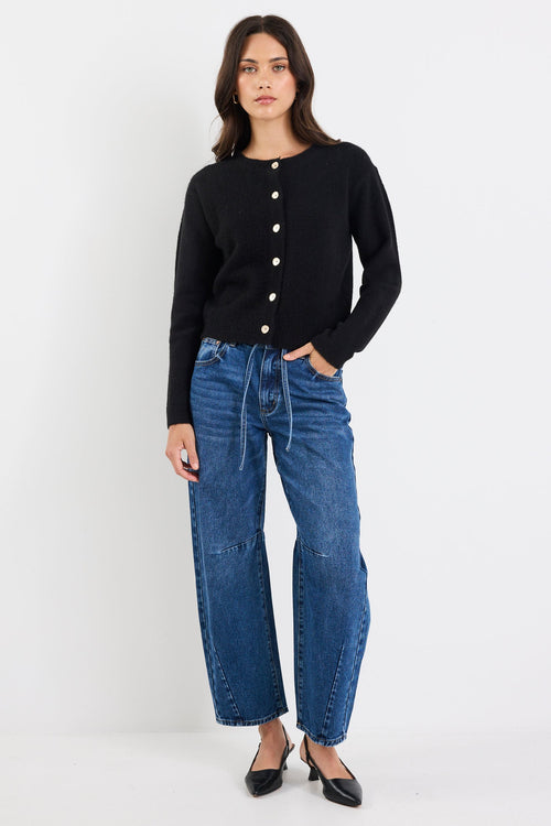 Woman wearing a black cardigan and blue jeans on a white background