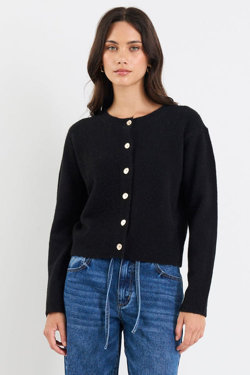 Person wearing a black cardigan and blue jeans on a white background