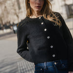 Woman wearing a black cardigan with white buttons in an urban setting