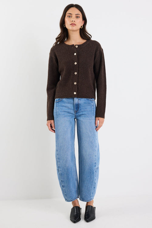 Woman wearing a brown cardigan and blue jeans on a white background