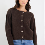 Woman wearing a brown cardigan with white buttons on a white background