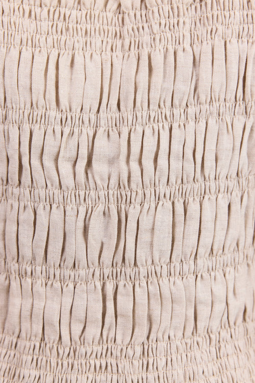 Close-up of a light beige or oatmeal-colored fabric with horizontal smocked or gathered texture.