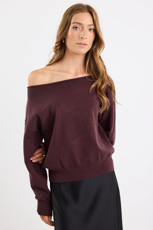 Woman wearing a burgundy off-shoulder sweater on a white background
