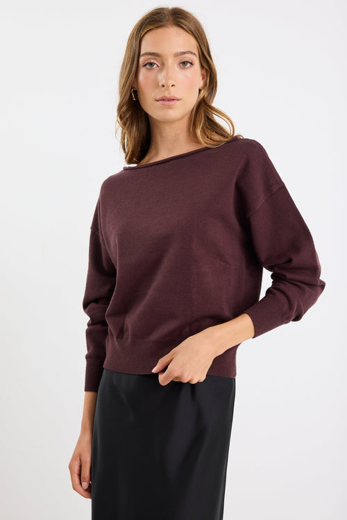 Woman wearing a dark purple sweater against a white background