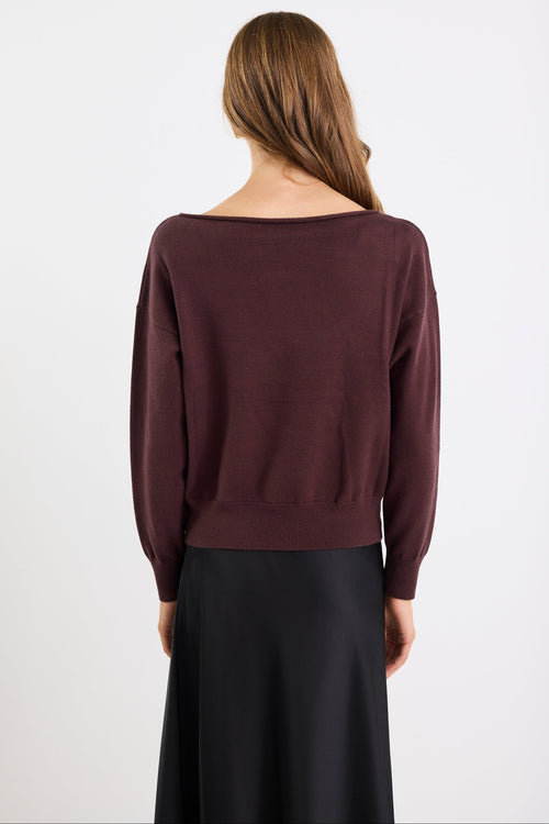 Woman wearing a dark purple sweater and black skirt on a white background