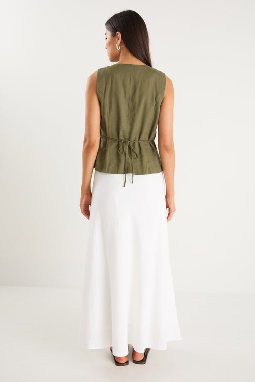 the model wears a green linen vest with a white maxi skirt