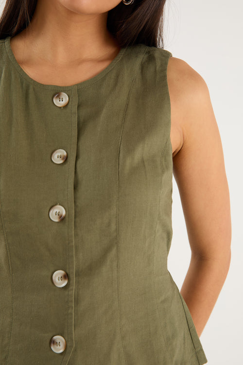 the model wears a green linen vest with a white maxi skirt