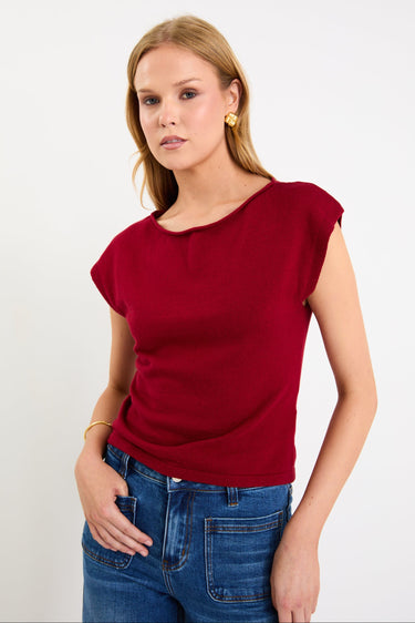 Model wearing a cherry red sleeveless knit top with a boatneck neckline