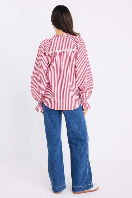 Model wears a red and white striped long sleeve shirt with button down front. 