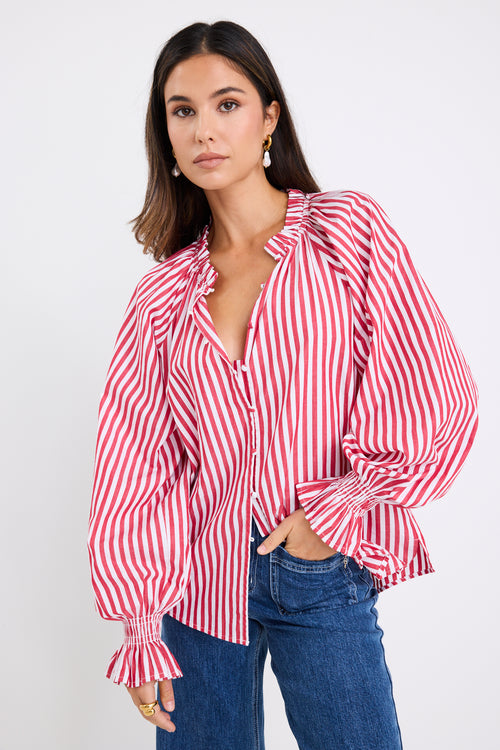 Model wears a red and white striped long sleeve shirt with button down front. 