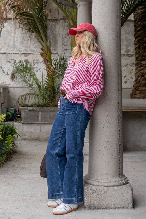 Model wears a red and white striped long sleeve shirt with button down front. 