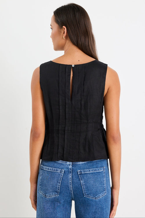 Woman wearing a black pintuck top with blue jeans