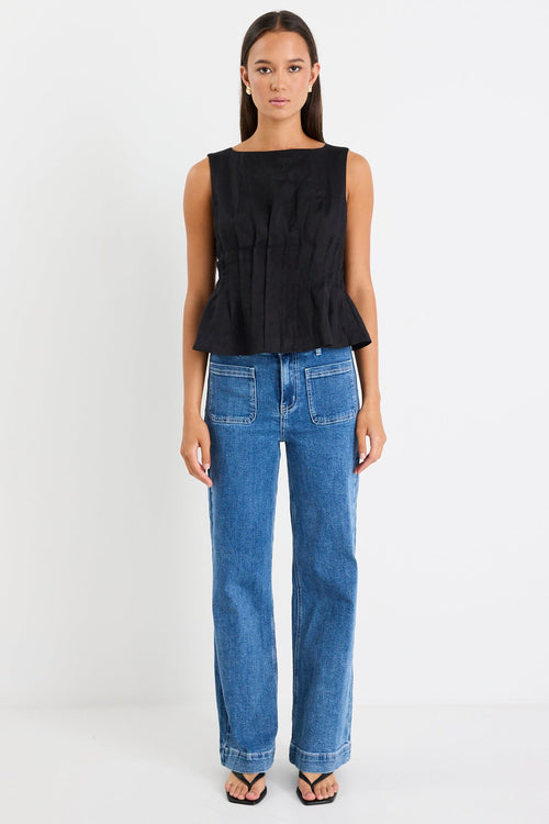 Woman wearing a black pintuck top with blue jeans