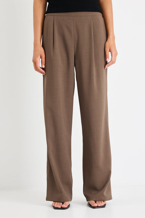 Person wearing brown pants and a black top on a white background