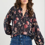 Woman wearing a floral blouse and blue jeans on a white background