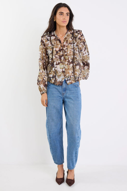 Woman wearing a floral blouse and blue jeans on a white background