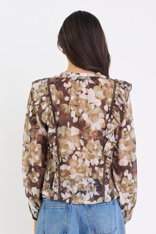 Person wearing a floral blouse and blue jeans on a white background