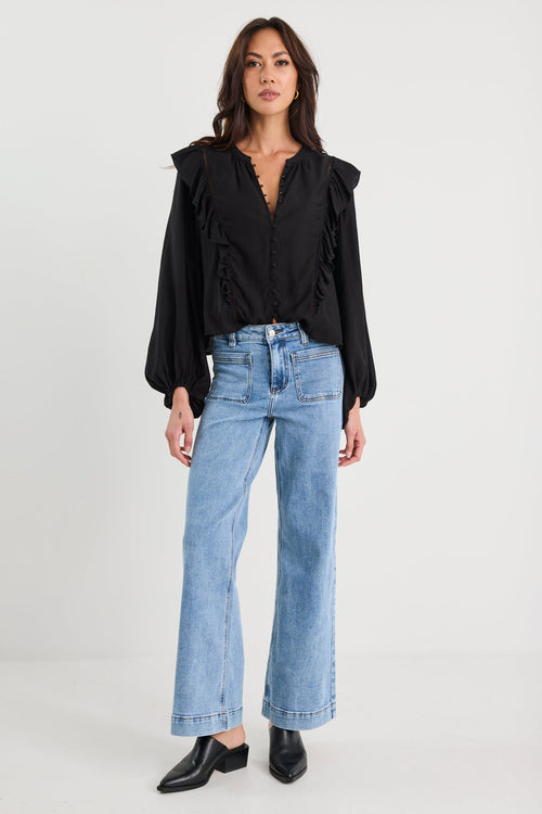 Woman wearing a black blouse and blue jeans on a white background