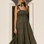 Woman in a long dark dress standing on a white architectural staircase.