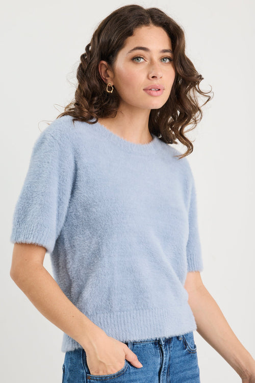Woman wearing a light blue sweater and jeans on a white background