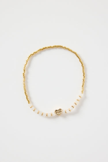 Ivory and gold beaded bracelet with a small heart charm, featuring gold cube beads and ivory accents. Delicate women’s jewellery perfect for gifting or stacking, photographed on a clean white background