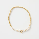 Gold and ivory beaded bracelet with a small gold heart charm in the centre, photographed on a clean white background.