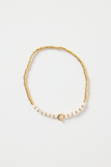 Gold and ivory beaded bracelet with a small gold heart charm in the centre, photographed on a clean white background.
