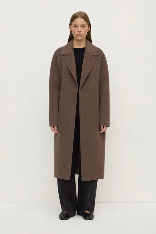 Person wearing a brown coat on a white background