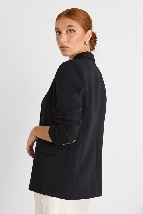 model wears black blazer with cream skirt