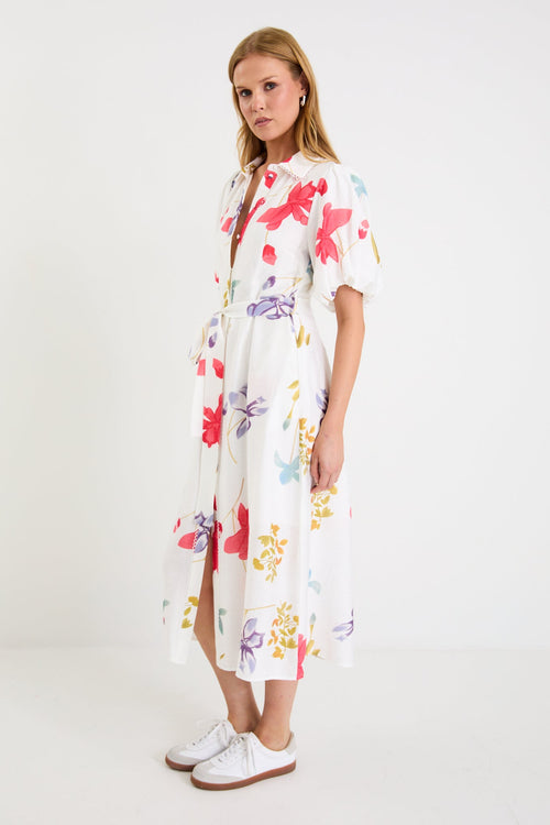 Model wearing a cream midi shirt dress with colourful poppy floral print, puff sleeves and a waist tie.